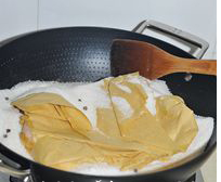 盐焗鸡翅,腌制好的鸡翅用两层油纸包起来，埋入炒锅中炒热的盐中。