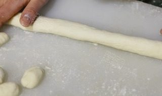 泡菜意大利面疙瘩,把处理好的土豆泥放到木板上，在木板上撒上一些面粉；双手搓揉直至面团光滑；将大面团分成拳头大小的面团，将其擀成约3厘米厚的长条。
