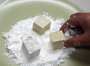 焦溜豆腐,在大盘上倒上玉米淀粉，将豆腐沾上干粉，一边沾一边放入锅内煎。