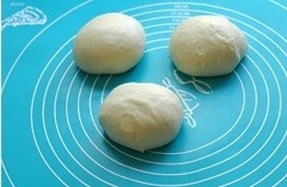 北海道中种吐司 ,揉好的面团先在面包机里盖上盖子，松驰15分钟后取出。平均分成三个面团，将其滚圆，盖上保鲜膜松驰15分钟。、