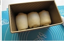 北海道中种吐司 ,将整形好的面团整齐的放入吐司模具中。
