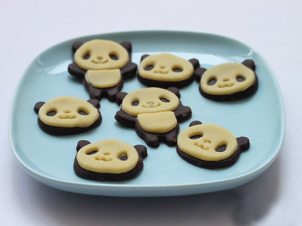 小熊猫饼干,可可面团操作完毕后同样操作原色的面团，将小熊猫的表情和姿势部分依次摆在可可打底的小熊猫形状上