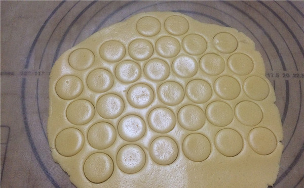 蛋黄纽扣小饼干,将面团放硅胶垫上用擀面杖擀成约3mm的面片。用小圆模或大号裱花嘴口按压出圆形