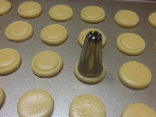 蛋黄纽扣小饼干,用小一圈的裱花嘴口在小圆片中间印一个浅点的圆圈印子，不要把圆片印断