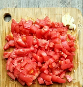 番茄肥牛,然后捞出来用凉水冲冲，剥皮，切成番茄丁。蒜拍一拍，切碎。