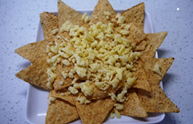 芝士肉酱玉米片,玉米片平铺在盘中，将大半马苏里拉奶酪碎均匀撒在表面