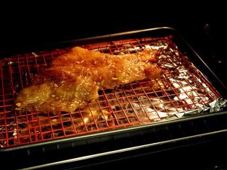 蜜汁叉烧,腌制完成，烤箱提前预热至200度，将叉烧肉整齐排在烤网上，底部放一不沾烤盘接油。记得垫上锡纸