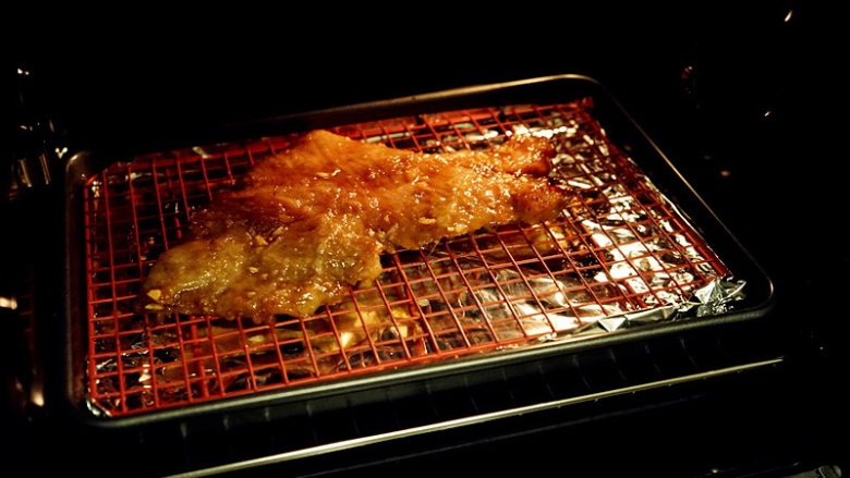 蜜汁叉烧,腌制完成，烤箱提前预热至200度，将叉烧肉整齐排在烤网上，底部放一不沾烤盘接油。记得垫上锡纸