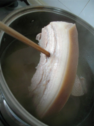 蒜泥白肉,煮至用筷子插入不会冒血水即可，不要煮的太久，太软烂不好切片。煮好后放在汤里浸泡约15分钟。