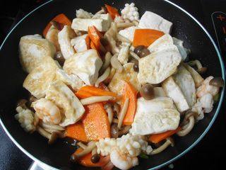 海鲜豆腐煲,加入胡萝卜和豆腐，加盐和蚝油调味；