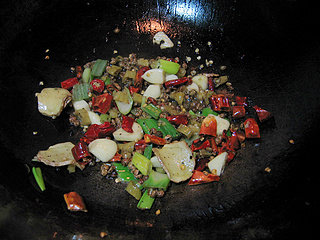 椒麻水煮鱼片,锅中入一点底油，油热后下入葱姜蒜、泡椒、小米椒、花椒小火炒香。