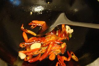 山寨湘西土匪鸭,锅中留底油，下蒜煸香后，倒入辣椒煸炒。