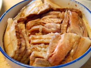 咸烧白,将切好的肉片在料汁中浸一下，肉皮朝下整齐地码在一个大碗内。