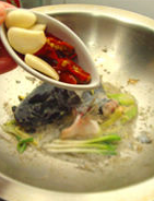 大蒜泡椒焖鲇鱼,鱼身煎好后取出，留鱼头鱼尾在锅中，放入泡椒和蒜头，泡椒水再次炒香。