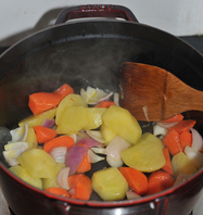 红烧土豆牛腩,锅中油中火烧至六成热，依次放入胡萝卜、土豆和洋葱，煸炒至八成熟（土豆透明边缘有些焦黄），盛出备用。
