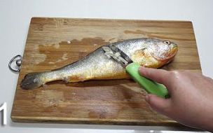 香煎黄花鱼,先用刮鳞刀将鱼身去鳞。