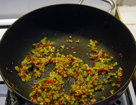 鱼香煎鸡腿,放入葱花（留一些葱花最后作装饰）、姜末、蒜末炒香，加入红、绿尖椒末一起炒。