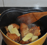红焖猪蹄,倒入一汤匙料酒和姜片炒匀。