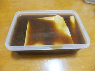 豆皮猪皮冻,过滤的汤汁倒在豆腐皮的上面，剩下的继续熬煮至溶化，还有一些猪皮粒没有溶化，倒在另一盒的豆腐皮上面，