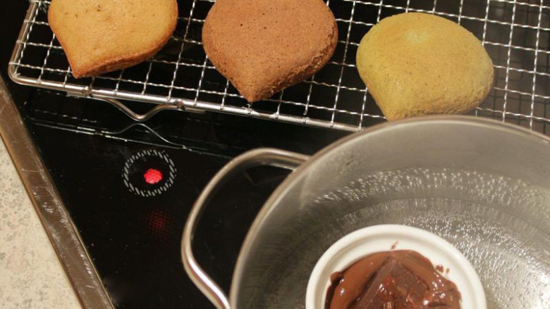 刺猬栗子小蛋糕,栗子迷你蛋糕放涼。 巧克力隔水加热致溶化。 把全部的栗子蛋糕分成两部份，第一份是做成栗子造型：在迷你蛋糕下缘部份涂上巧克力，模拟成栗子壳的样子。
