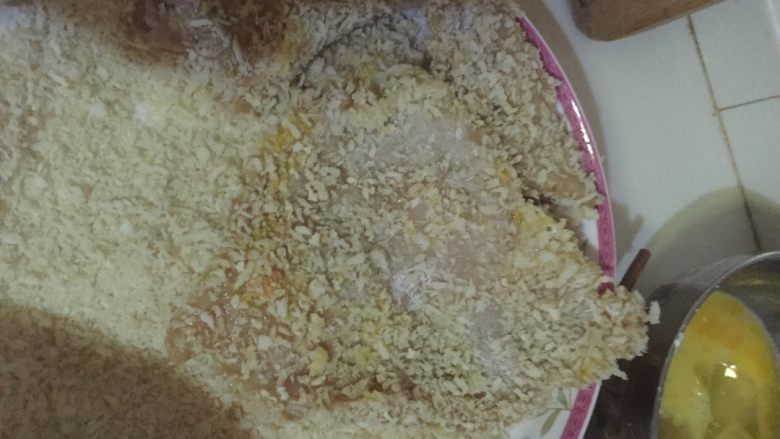 秘制大鸡排,如图第一步先把鸡肉片在淀粉里蘸一下，使鸡肉片被淀粉薄薄地包裹住，第二步，将裹好了淀粉的鸡肉片在蛋液中蘸一下，也是要全部蘸满，第三步：将沾满蛋液的肉片平铺在面包糠上，两手按压使之均匀裹上面包糠