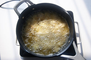  菠萝咕噜肉,炸完后开大火将锅里的油继续加热，油温八九成热时，倒入肉片复炸至微金黄。