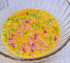 玉子烧,碗中打入鸡蛋，加入培根丁和香葱丝，顺一个方向尽量搅匀。