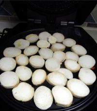 香煎杏鲍菇,预热完成后，将杏鲍菇片铺在电饼铛里；启动“大饼/馅饼”功能