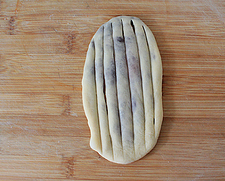 红豆沙面包卷,将包好红豆沙的面团按扁、擀成长舌状，用刀划出纵向纹路。