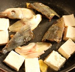 紫苏鱼头豆腐煲,平底锅入少许油，放入腌制过的鱼头，豆腐若是很嫩的可以粘些淀粉再入锅同煎，结实一点点豆腐也可以直接入锅煎，不需要粘淀粉，看买到的是什么豆腐，我个人比较喜欢南风的嫩豆腐，外酥里嫩鲜香烫口的感觉在冬天很美