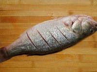 泰式清蒸柠檬鲈鱼,将收拾干净的鲈鱼抹干水分，两面分别割上三刀，这样方便鱼肉入味。