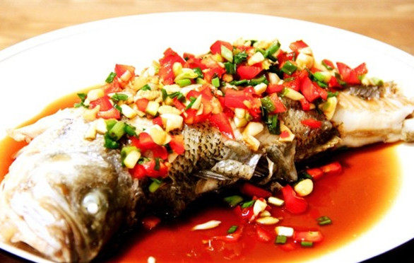 泰式清蒸柠檬鲈鱼,蒸好的鱼取出摆盘，将肚子里的姜片取出来，然后将调好的调味料倒在鱼身上即可上桌。