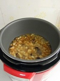 鸡汤菌菇焖饭,将炒好的蘑菇连同汤汁倒入电饭煲，用勺子将蘑菇铺匀。