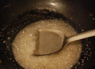 挂霜花生,直到感觉锅中水收干，糖稀变得浓稠，泡泡由大泡变成细密略带金黄的小泡，搅拌时有粘稠感可以刮在铲子上。