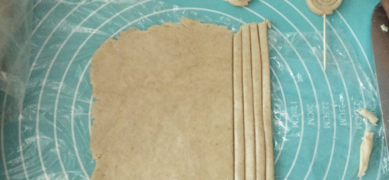 粗粮棒棒糖饼干,裁切成长条状，然后从一端卷起，最后用牙签固定，整齐码放在铺好油纸的烤盘上