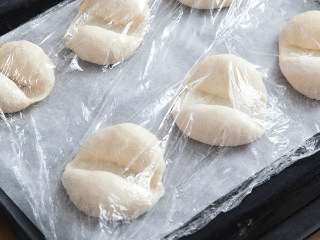 海地白面包,用双手托起面团，放人烤盘。盖上保鲜膜二次发酵。室温醒发20-25分钟