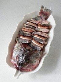 麒麟鲈鱼,将香菇片，鱼片，口蘑片和午餐肉片依次摆放在鱼骨上。
