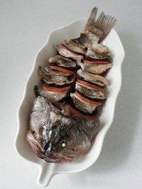 麒麟鲈鱼,蒸好的鱼端出，将上面的姜片和葱段拣去不用。