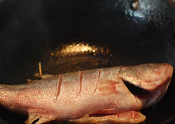 锡纸包鲈鱼,炒锅添油，烧热后，先放几片姜片略煸，再将鲈鱼放入锅中，煎到两面焦黄，盛起，放到锡纸中央。