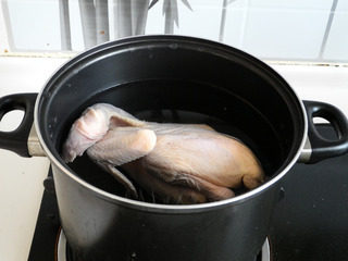私房白切鸡,将三黄鸡放入加入温水的锅中。