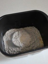 酒渍提子面包,再将高筋面粉倒入面包桶。