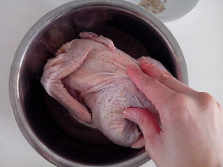 手撕盐焗鸡,将混合好的盐和胡椒粉均匀的抹到鸡的身上与肚子。