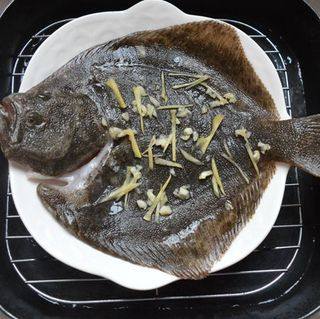 清蒸多宝鱼,锅里烧开适量水，把多宝鱼放进，并在鱼肚和鱼身上放上适量姜丝和蒜粒。盖上锅盖大火蒸13分钟。