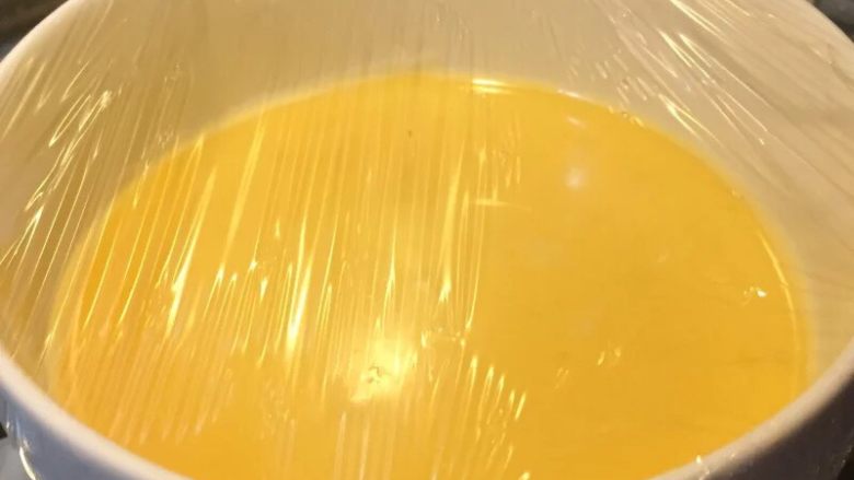 宝宝辅食果香牛奶鸡蛋羹,如图过滤好的蛋液倒入容器中，盖上保鲜膜，用牙签扎洞帮助透气，上锅蒸15-20分钟，中间不要掀盖子