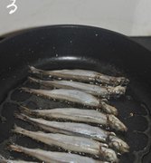 香煎椒盐多春鱼,平底锅烧热，放入一茶匙色拉油，把腌制好的多春鱼用厨房纸巾拭干表面水份，排入锅中。
