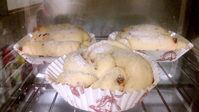 蔓越莓奶香面包,烤箱预热180度。在面团表面撒一层糖粉，放入烤箱，180度烤20分钟。
