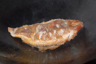 干烧福寿鱼,炒锅下油，下福寿鱼煎至两面金黄。