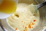 香橙海绵杯子蛋糕,将玉米油和橙汁的混合液里倒入蛋糊，用刮刀翻拌好。