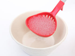 杨枝甘露,备好的西米用漏勺滤出水后，舀一勺放入碗中。