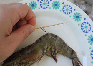 照烧虾,用牙签在虾的第二关节处插进去。然后挑出虾线。